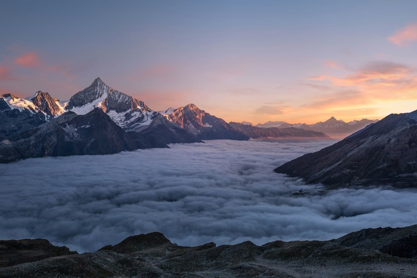 Alpine peaks above a sea of clouds at sunset